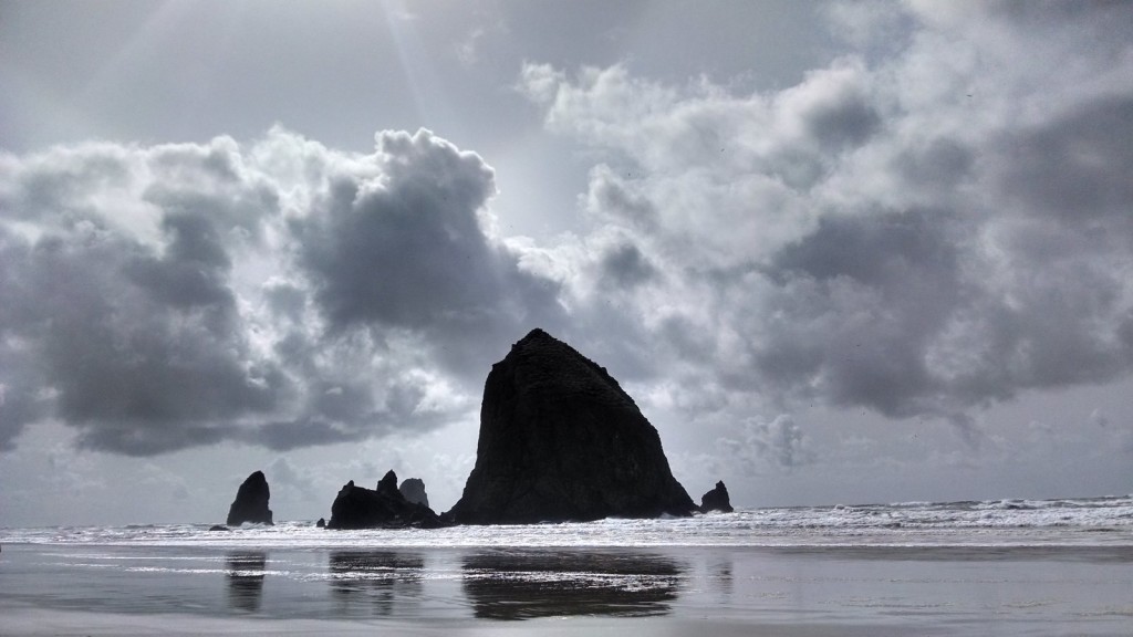 Haystack Rock on a partly cloudy day.